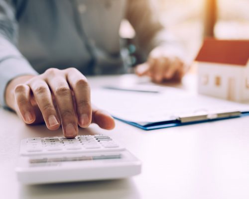 Close up of finger businessman using calculator calculate budget about house contract mortgage in the office room.